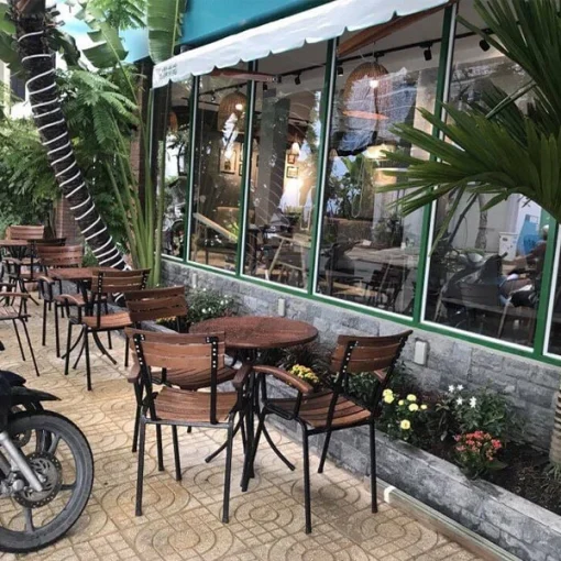 Bàn Fansipan Moon 01 – Bàn tròn chân cong và ghế có tay nan gỗ trong khu ngồi trước quán