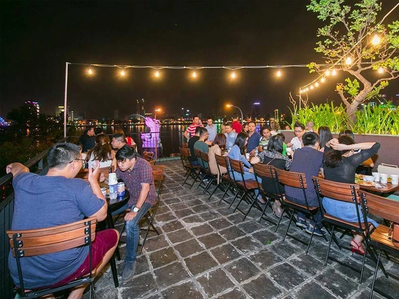 Bàn Fansipan Patio 02 | Xcom.vn Bàn Fansipan Patio 02 – Bố trí nhiều bàn và ghế nan gỗ ở khu ngồi ngoài trời buổi tối; ảnh là bối cảnh phối nhiều món