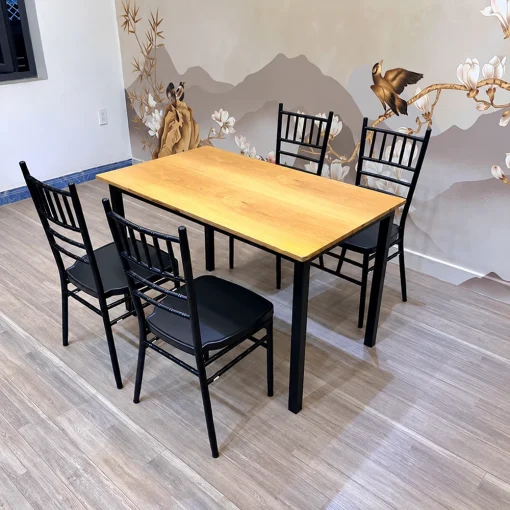 Bộ QN03 với một bàn mặt gỗ sáng và bốn ghế đơn tựa nan đứng trong không gian phòng
