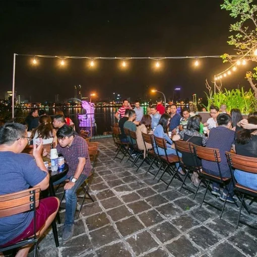 Ghế Fansipan Patio 02 – Dãy ghế tựa nan chân xếp bố trí quanh các bàn trong không gian ngoài trời buổi tối